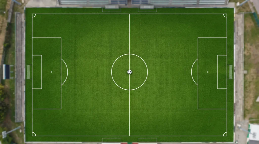 Campo de fútbol visto desde arriba con las líneas del terreno de juego marcadas y un balón en el centro